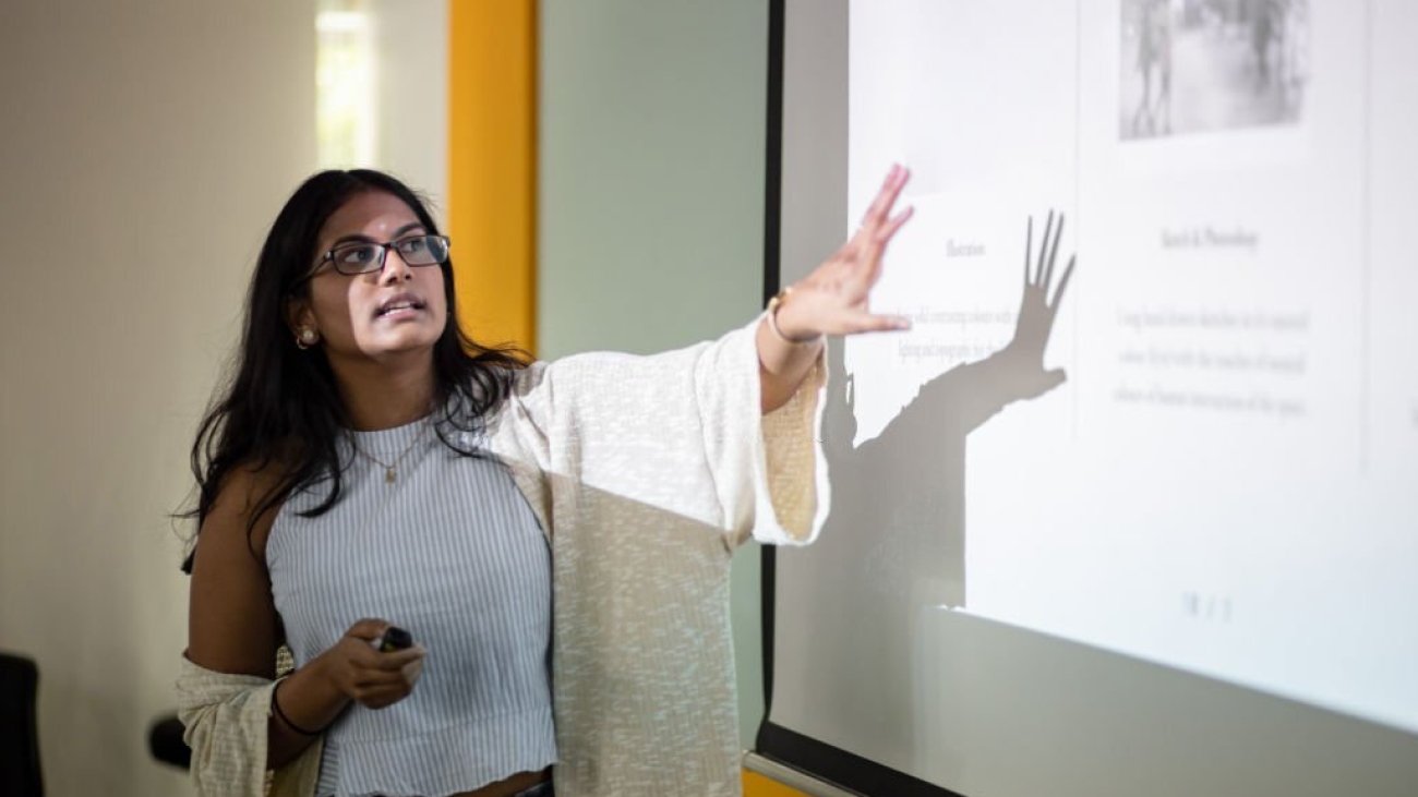 Asian college student is making a presentation in front of projector screen