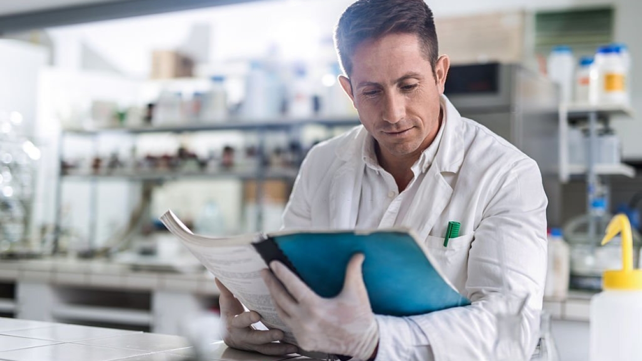 Mid adult male scientist reading scientific data in a laboratory.
